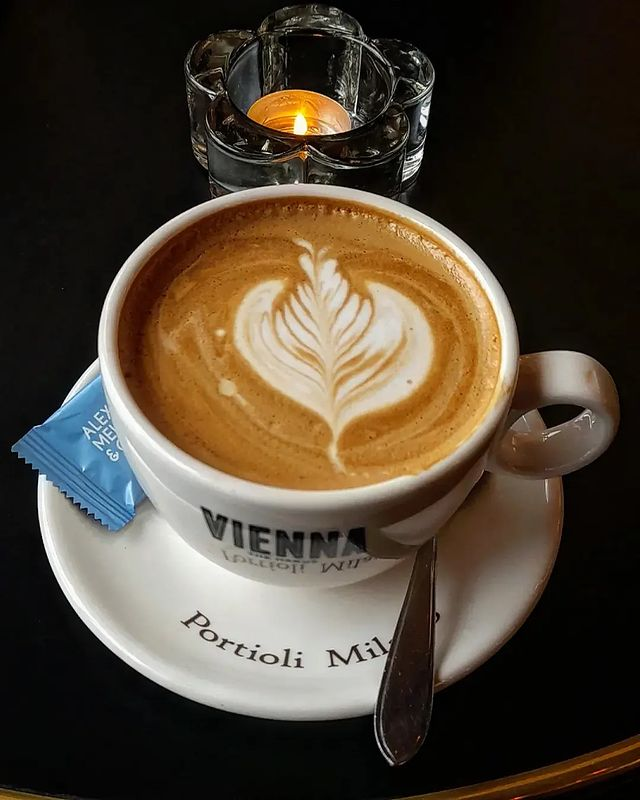 A cup of cappuccina with a candle in a café